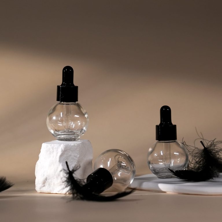 Clear spherical glass skincare bottle with black dropper